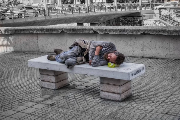 Hombre sin hogar duerme en el banco de piedra en el centro de —  Fotos de Stock