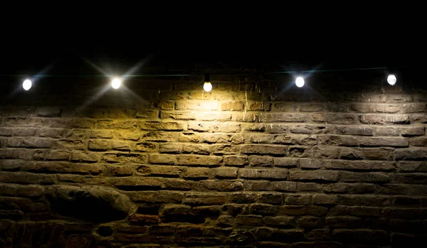 Lâmpadas incandescentes e led na parede de tijolo — Fotografia de Stock