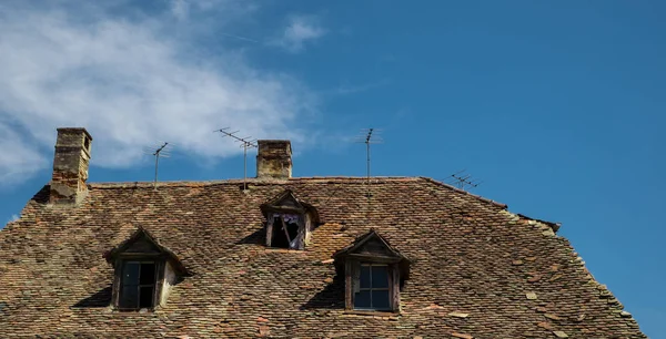 Alte Dachziegel mit Fernsehantenne und Schornsteinen — Stockfoto
