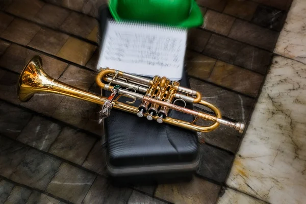 old trumpet with musical notes and green hat on the pavement box
