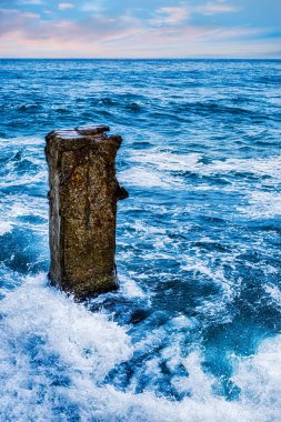 Deniz dalgaları eski beton direğe çarparak