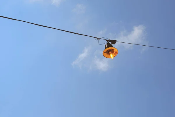 Vintage rusty street light lit on the wire on day — Stock Photo, Image