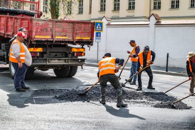 İşçiler bozuk asfalt yolu onarıyor