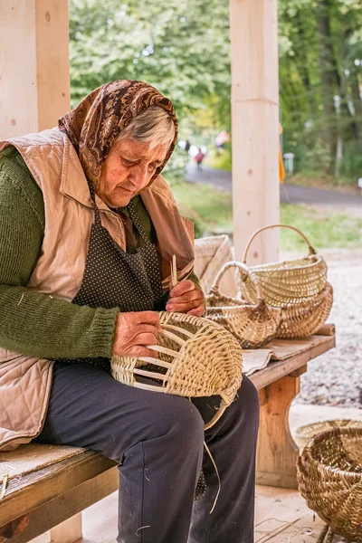 一个老罗马尼亚妇女编织柳条篮子 — 图库照片