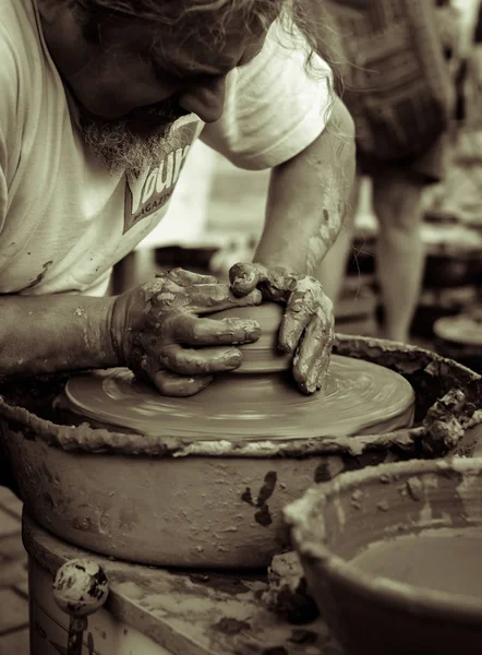 Manos de un alfarero moldeando una olla de barro en una rueda de alfarero — Foto de Stock