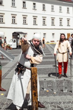 bir ortaçağ şövalyesi gibi giyinmiş bir adam h ile su şişesi keser