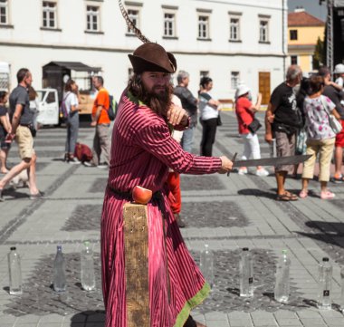 bir ortaçağ şövalyesi gibi giyinmiş bir adam ile farklı bir nesne keser