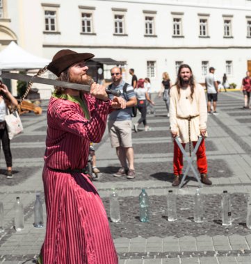 bir ortaçağ şövalyesi gibi giyinmiş bir adam ile farklı bir nesne keser