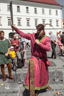 bir ortaçağ şövalyesi gibi giyinmiş bir adam h ile su şişesi keser
