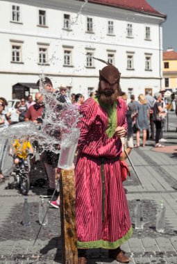 bir ortaçağ şövalyesi gibi giyinmiş bir adam h ile su şişesi keser