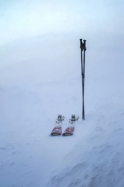 Pair of skis and sticks stuck in snow in the winter storm