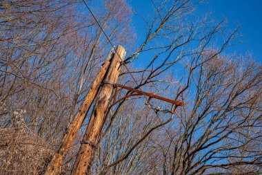 Romanya 'nın Sibiu kentindeki orman yakınlarındaki eski bir tramvaydan eski tahta direklerle elektrik kabloları