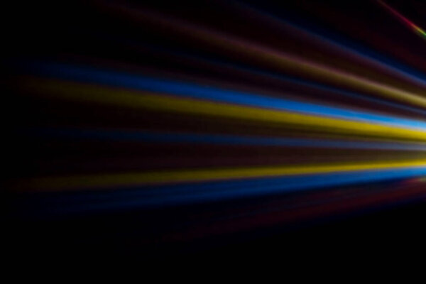 colored light beams from reflector through the foggy night sky