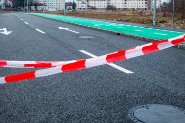 Kırmızı ve beyaz bariyer bandı, inşaatta yeni yola araba ve bisikletçilere erişimi kısıtlıyor