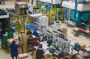 Sibiu City, Romania - 08 March 2021. Group of workers working on the production auto components line in factory, aerial view