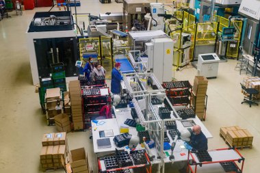 Sibiu City, Romania - 08 March 2021. Group of workers working on the production auto components line in factory, aerial view