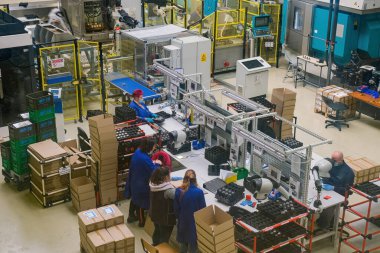 Sibiu City, Romania - 08 March 2021. Group of workers working on the production auto components line in factory, aerial view