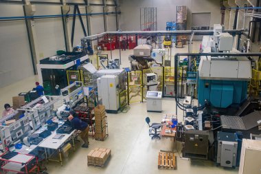 Sibiu City, Romania - 08 March 2021. Group of workers working on the production auto components line in factory, aerial view