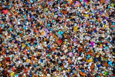 A close-up shows colorful, natural pebbles creating a textured surface