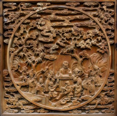A detailed Asian bas-relief carving scene with figures, likely narrative in nature, arranged within a landscape of stylized trees and clouds