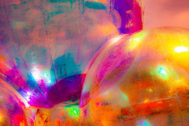 Canlı, soyut bir sanat eseri. Parlak, parlak bir yüzeye yakın çekim. Renkli bir ışığı yansıtıyor. Baskın renkler kırmızı, turuncu, sarı ve pembedir..