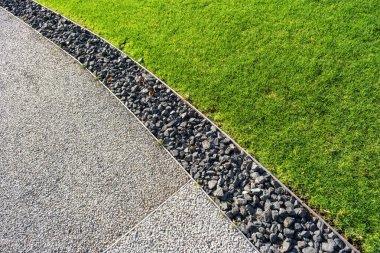 Yeşil çimen, küçük pürüzsüz çakıl taşları ve betondan oluşan çekici bir kompozisyon, peyzaj projeleri için ideal veya şık bir zemin olarak