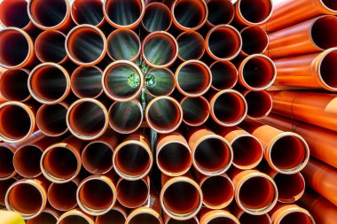 Polivinil klorürden yapılmış bir yığın turuncu boru.