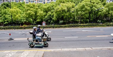 Shanghai, China - May 19 2025 people riding electric moped on the road in the morning