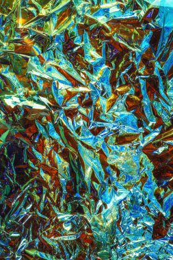 Son derece desenli, buruşuk metalik bir yüzey. Parlak, yansıtıcı alüminyum folyo gibi görünüyor. Karmaşık kıvrımlar ve kırışıklıklar kaotik, neredeyse soyut bir desen oluşturuyor..