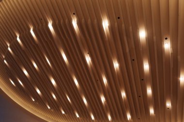 Dikdörtgen şeklinde paneller içeren modern bir mimari tavan. Küçük, eşit aralıklı ışıklar tavana gömülü, yumuşak, dağınık bir parıltı bırakarak.
