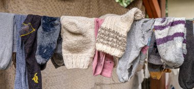 Eski köylü yün çorapları ipte, arkasında eski bir halı olan eski ahşap kancalarla.