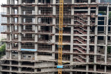 Dış duvarları olmayan çok katlı bir binanın tamamlanmamış zeminleri. Vinçli, monolitik konut binasının ön cephesi.