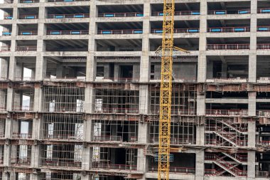 Dış duvarları olmayan çok katlı bir binanın tamamlanmamış zeminleri. Vinçli, monolitik konut binasının ön cephesi.