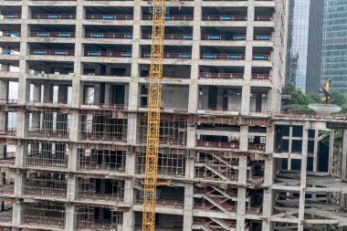 Dış duvarları olmayan çok katlı bir binanın tamamlanmamış zeminleri. Vinçli, monolitik konut binasının ön cephesi.