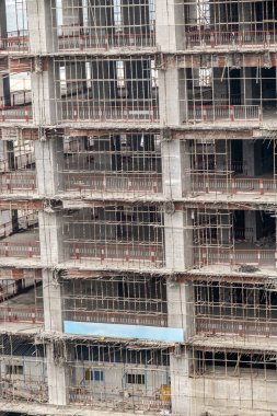 Dış duvarları olmayan çok katlı bir binanın tamamlanmamış zeminleri. Vinçli, monolitik konut binasının ön cephesi.