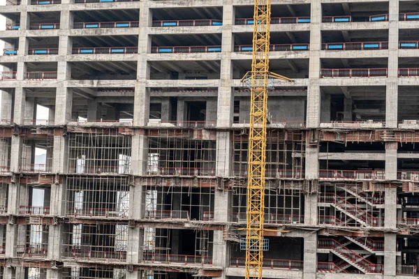 Dış duvarları olmayan çok katlı bir binanın tamamlanmamış zeminleri. Vinçli, monolitik konut binasının ön cephesi.