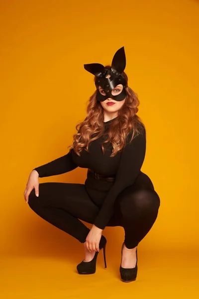 Сексуальная модель plus-size в кожаной маске зайчика, сидящая на своем привидении — стоковое фото