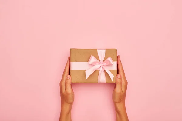 Manos sosteniendo hermosa caja de regalo en flatlay rosa Imagen De Stock