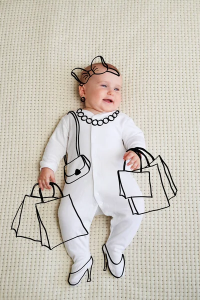 Sorrindo bebê menina deitada na cama com sacos de compras — Fotografia de Stock