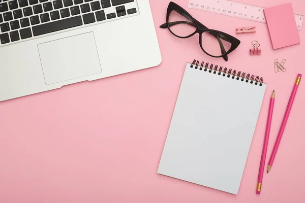 Красива плоска лінія з ноутбуком, окулярами та канцелярськими приладами на рожевому де Стокове Фото