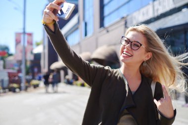 Mutlu kadın şehirde Mobil kamera kullanarak selfie alarak