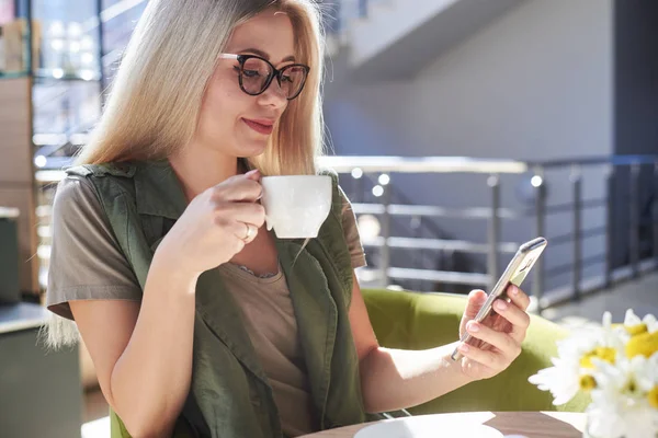 Hermosa mujer usando el teléfono móvil en la cafetería — Foto de Stock