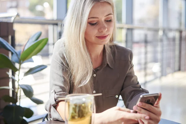 Vacker kvinna med telefon på café — Stockfoto