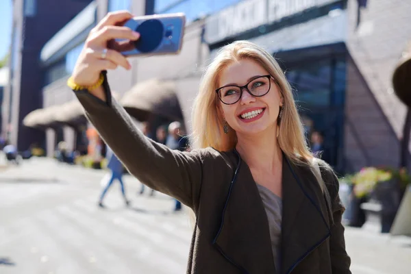 Mujer tomando selfie usando cámara móvil en la ciudad —  Fotos de Stock