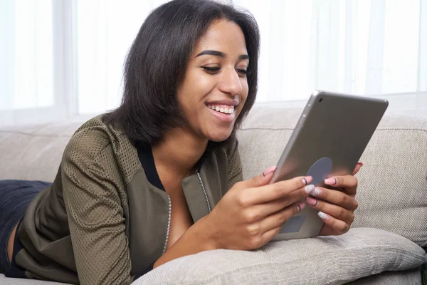 Tizenéves lány segítségével digitális tábla kanapéval otthon — Stock Fotó