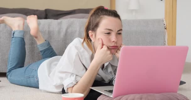 Verwirrte Frau benutzt Laptop auf Teppich zu Hause — Stockvideo