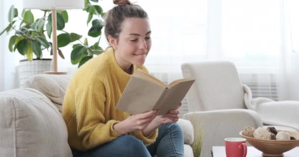 Женщина смеется во время чтения книги — стоковое видео
