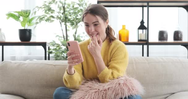 女性は自宅で携帯電話を使用して良いニュースを読むことに驚いて — ストック動画