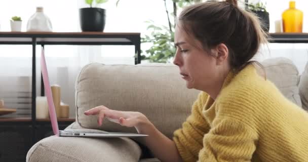 Femme utilisant un ordinateur portable couché sur le canapé à la maison — Video