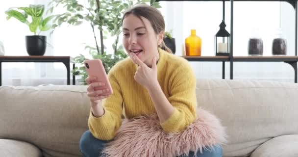 Жінка здивована читанням хороших новин за допомогою мобільного телефону вдома — стокове відео
